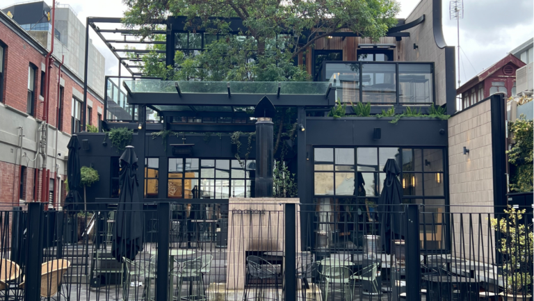Outdoor view of The Arborist restaurant in Geelong, showcasing modern black exterior design with greenery and an upper-level terrace.